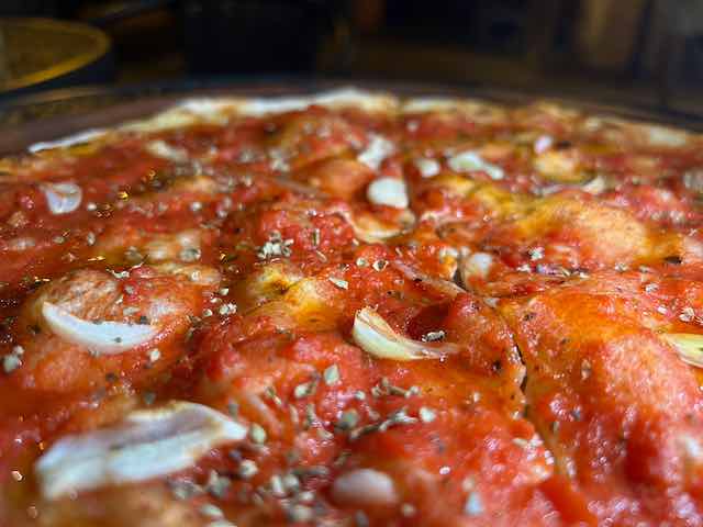 Margherita pizza topping of garlic flakes and oregano from close up